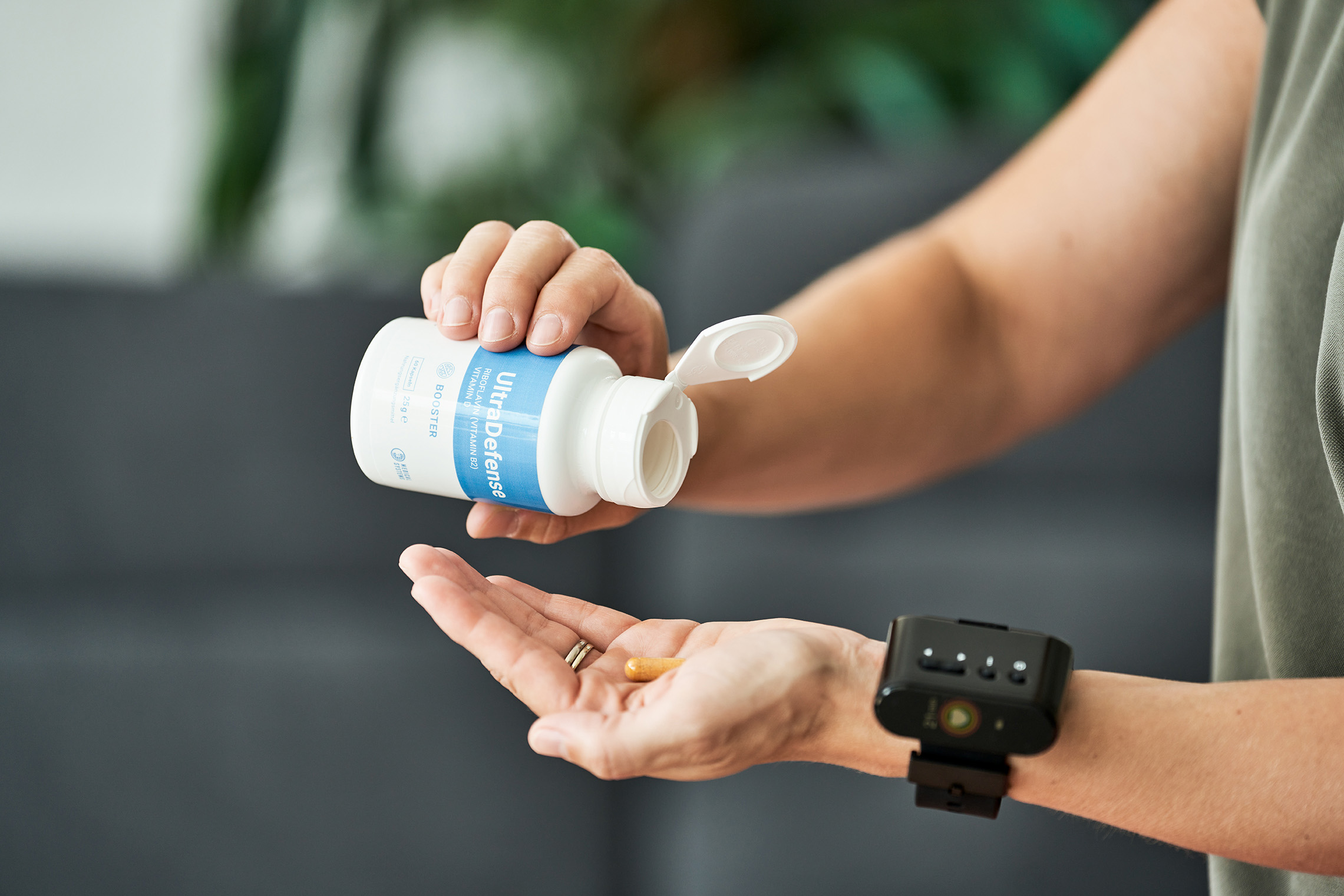 Image showing a capsule being poured from the UltraDefense dietary supplement can onto the hand.